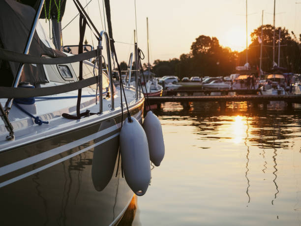 vue du coucher de soleil sur le voilier amarré sur la jetée dans le port, vue rapprochée sur la coque du voilier, la proue et les ailes - marina photos et images de collection