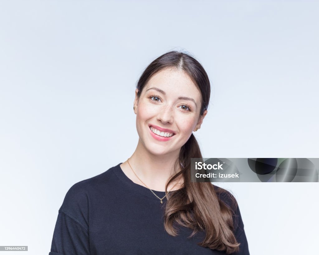 Happy young woman against white background Portrait of happy young woman with brown hair wearing black t-shirt against white background Formal Portrait Stock Photo