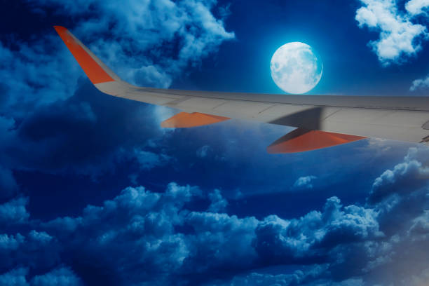 istock airplane wing in flight on a clear night with the moon- 1396442167