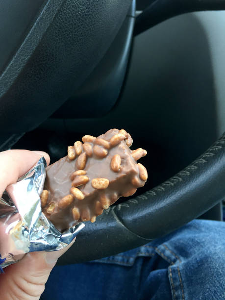 istock Hand holding chocolate in the car interior, eating chocolate 1396442393