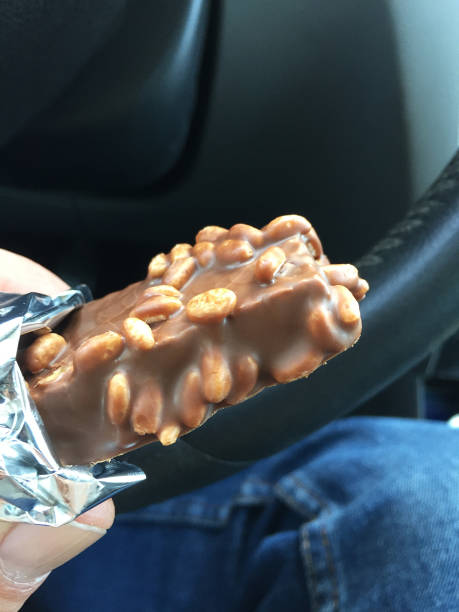 istock Hand holding chocolate in the car interior, eating chocolate 1396442429