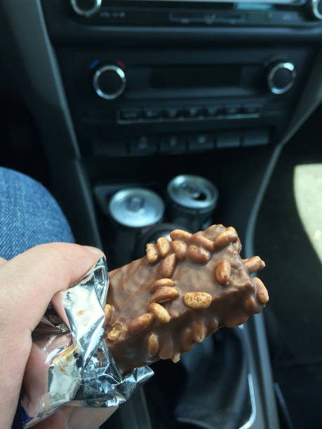 istock Hand holding chocolate in the car interior, eating chocolate 1396442459