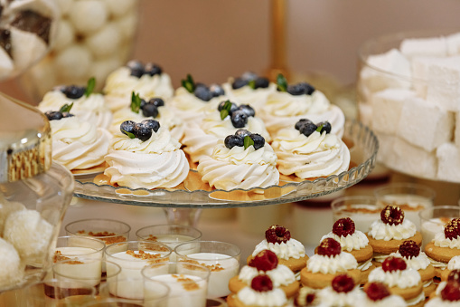 Wedding candy bar table. Cakes with cream and berries and other sweets. High quality photo.