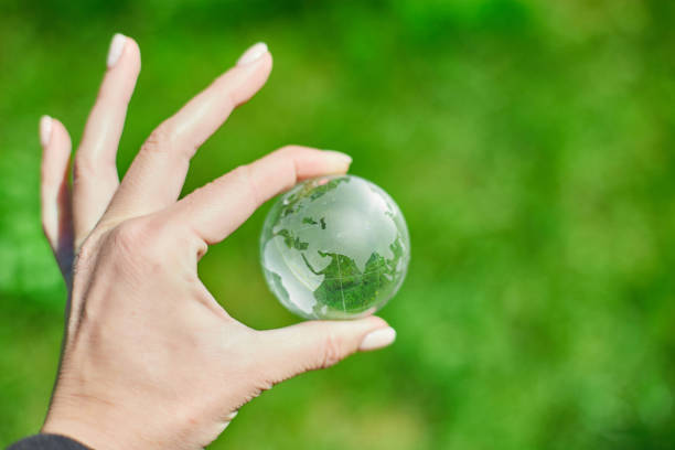 istock Human hand hold glass Earth globe on green grass background, Saving environment concept. 1396444601