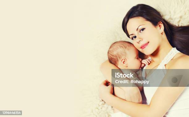 Portrait Of Mother With Sleeping Baby Lying On The Bed Together At Home Stock Photo - Download Image Now