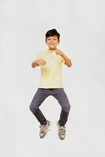 Young boy jumping in the air on neutral background. Studio shoot