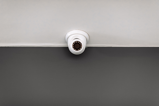 White security CCTV Camera or surveillance operating on ceiling inside room with copy space. High quality photo.