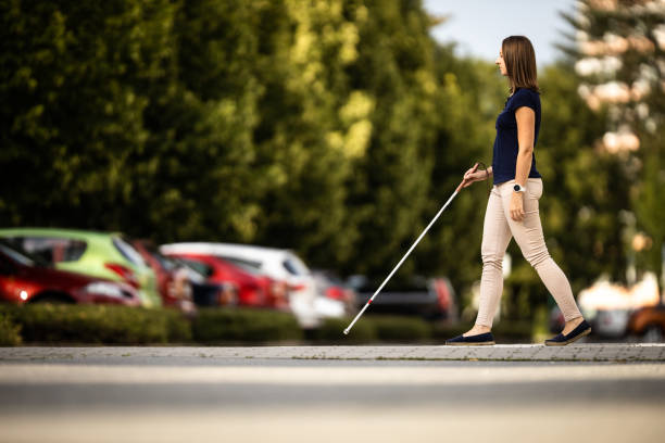 Blind woman walking on city streets, using her white cane Blind woman walking on city streets, using her white cane blind persons cane stock pictures, royalty-free photos & images