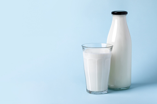 Bottle and glass of  milk on a blue background with space for your text