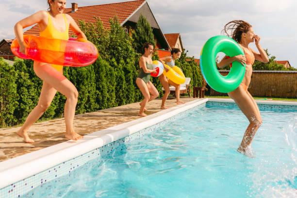istock Female friends jumping into the pool 1396453788