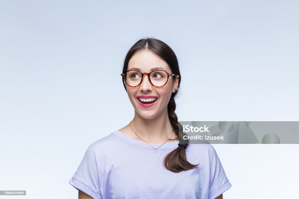 Surprised young woman looking away Excited young woman wearing lilac t-shirt looking away and laughing against white background. Formal Portrait Stock Photo