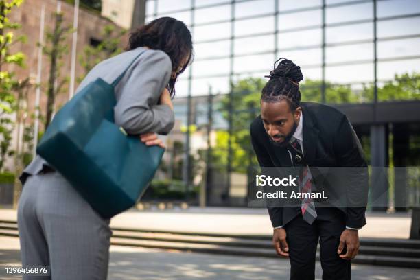 Black Male Lawyer And Japanese Female Client Bowing In Front Of A Building Stock Photo - Download Image Now