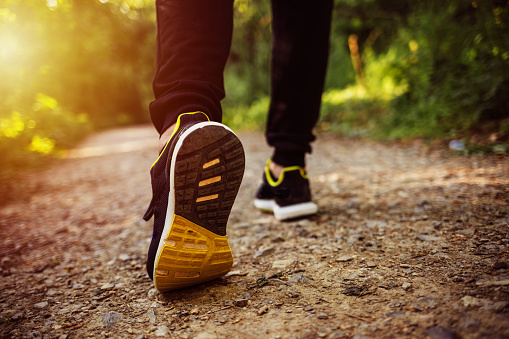 Close up shot of runner's shoes. Man running at autumn during sunrise. Closeup shot of a sporty man in starting position while exercising outdoors.