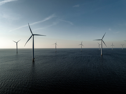 Wind turbines producing sustainable renewable energy in an offshore wind park in Flevoland, The Netehrlands. Drone point of view.