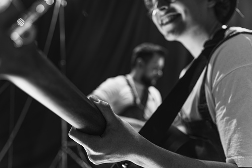 Black and white image. Repetition of rock music band at music studio. Cropped image of electric and acoustic guitar players at concert. Rehearsal base Concept of art, music, style. Out of focus effect