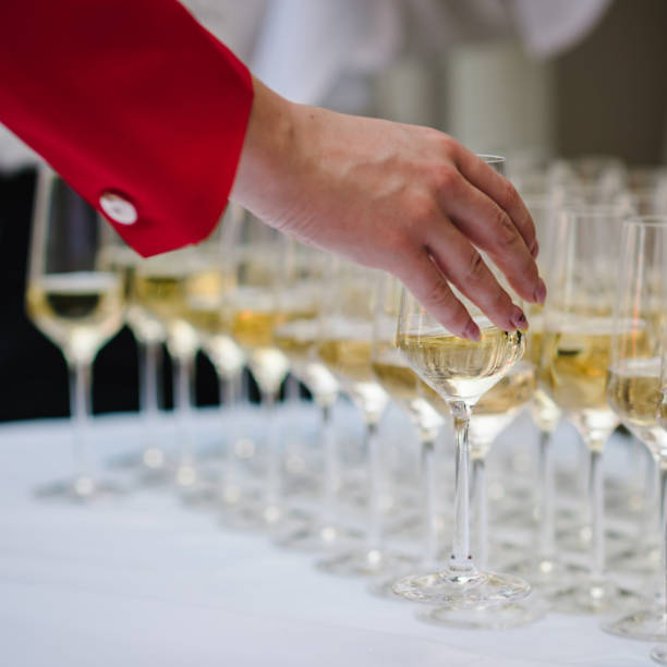 la donna prende un bicchiere di champagne flute con spumante bianco. file di bicchieri pieni di bicchieri da vino si chiudono in vista. concetto di servizio di ristorazione. - party business toast champagne foto e immagini stock