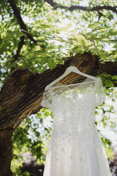 istock White wedding dress hanging on a tree outdoors in the garden. 1396462178