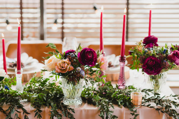 istock Table setting at the wedding reception. Floral compositions with beautiful ranunculus flowers and greenery, candles, laying and plates on a decorated table. 1396462210