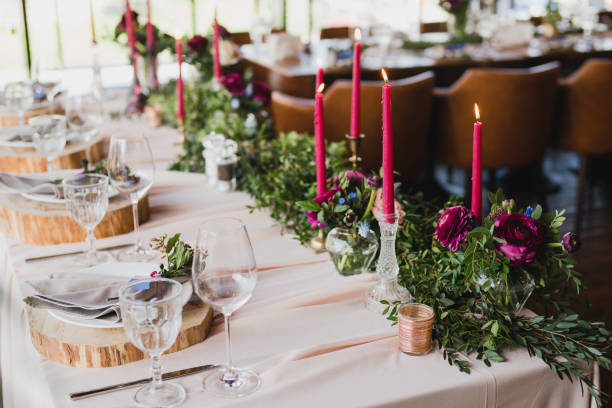 istock Table setting at the wedding reception. Floral compositions with beautiful ranunculus flowers and greenery, candles, laying and plates on a decorated table. 1396462329
