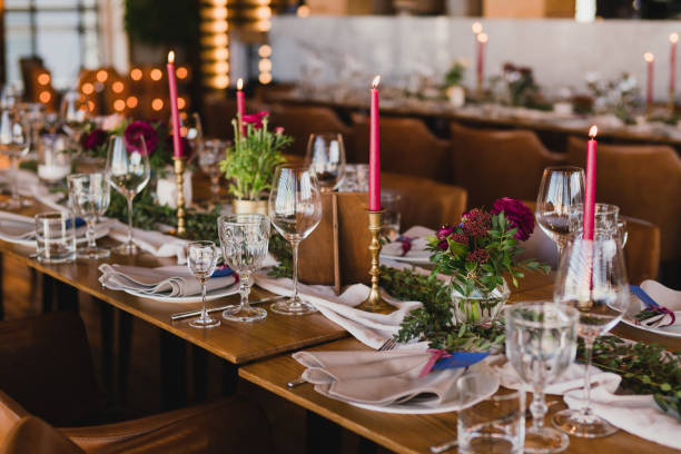 istock Table setting at the wedding reception. Floral compositions with beautiful ranunculus flowers and greenery, candles, laying and plates on a decorated table. 1396462445