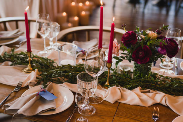 istock Table setting at the wedding reception. Floral compositions with beautiful ranunculus flowers and greenery, candles, laying and plates on a decorated table. 1396462475