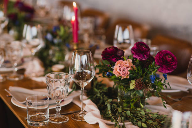istock Table setting at the wedding reception. Floral compositions with beautiful ranunculus flowers and greenery, candles, laying and plates on a decorated table. 1396463055