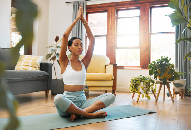 tiro de uma jovem esportiva meditando em casa - meditating - fotografias e filmes do acervo