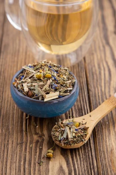 istock Small blue bowl with dry herbs and cup of tea on a rustic background. 1396464660