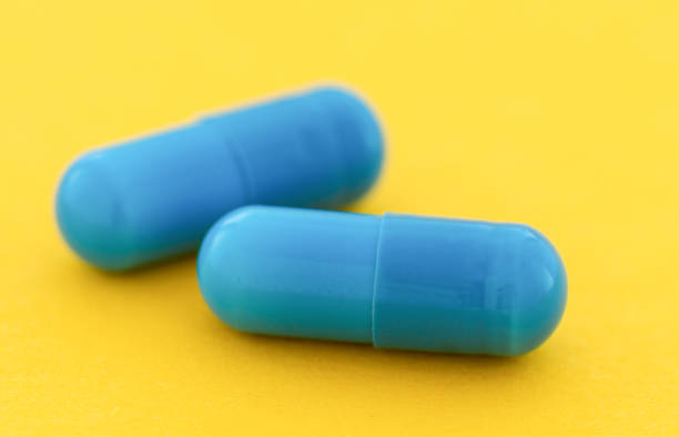 istock Blue capsule pills on a yellow background close up 1396465277
