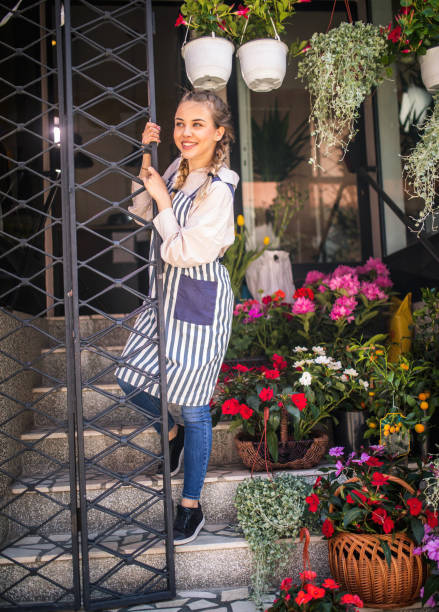 Young florist holding sign open and smiling, small business