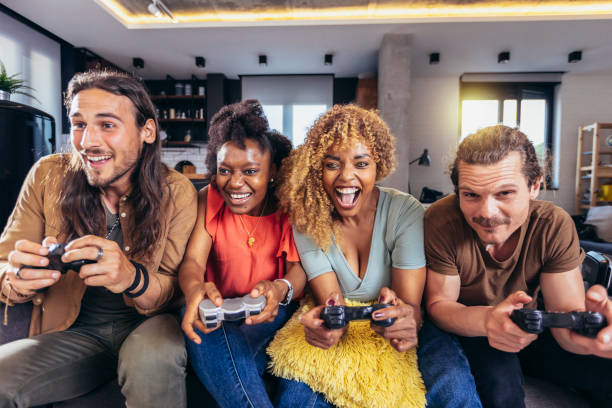 Group of friends playing video games. Happy fellows having fun at home with joysticks playing video games, gesturing and screaming, enjoying time together.