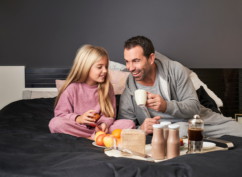 father and daughter having breakfast in bed