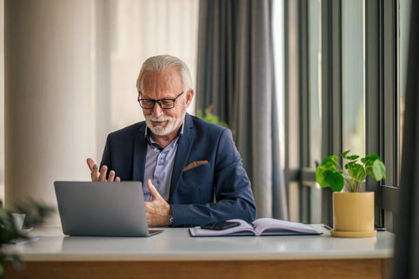 istock Happy senior professional gesturing while looking at laptop on desk in office. 1396470834