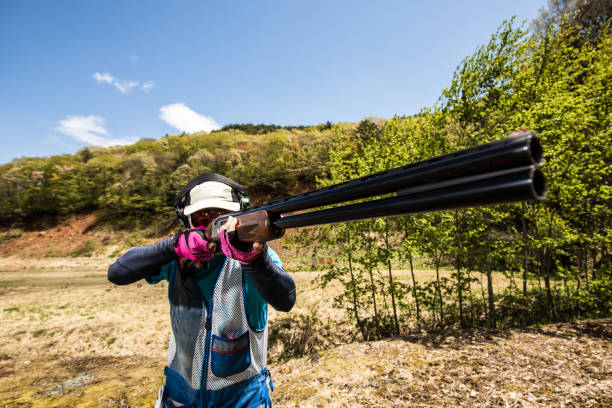 A barrell of a hunting rifle in focus with the hunter out of focus
