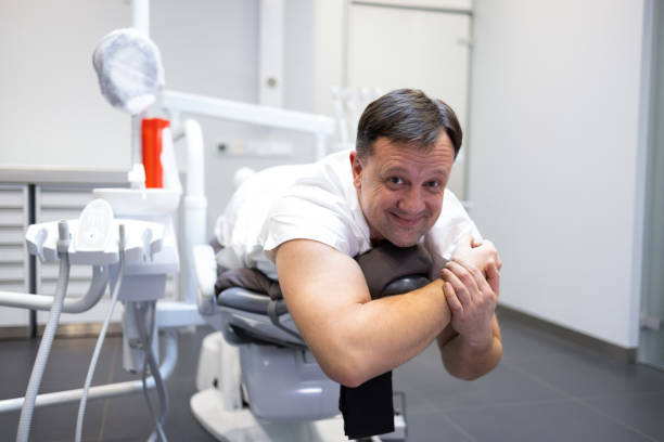 A modern dental office features a sleek blue and white dental chair. The metal frame gleams under the ceiling lights, creating a clean and professional atmosphere.