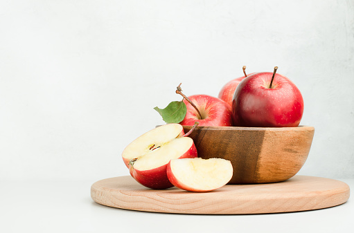 wooden plate with fresh red apples on a light background