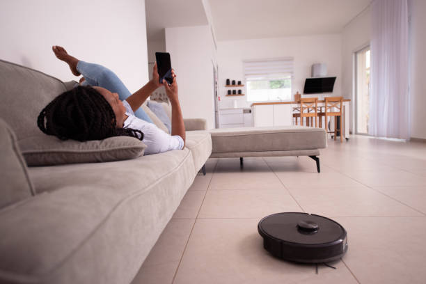 istock A woman controlling a robot vacuum cleaner at home via a smartphone application. 1396474854