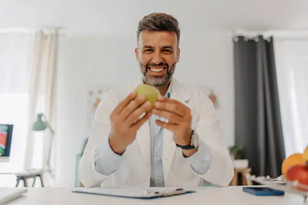 Doctor holding an apple and looking at camera