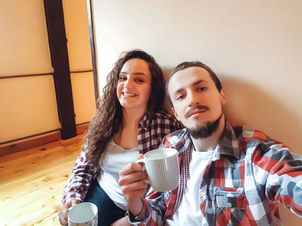 Close-up of  man and his senior mother standing together outside on a patio with cups of coffee in the morning