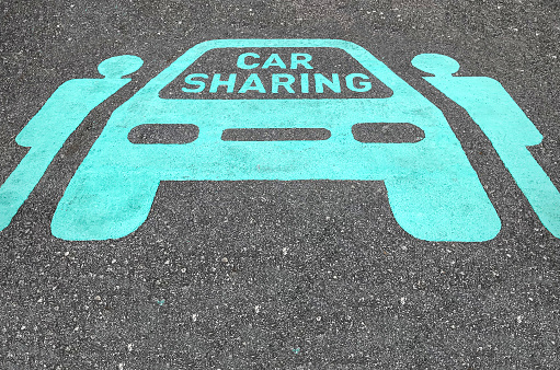 Car sharing parking symbols painted onto asphalt road. Car sharing service or rental concept. Sharing economy and collaborative consumption.