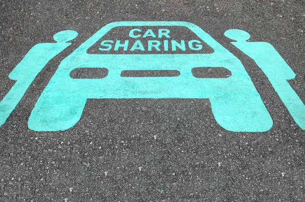 Car sharing parking symbols painted onto asphalt road. Car sharing service or rental concept. Sharing economy and collaborative consumption.