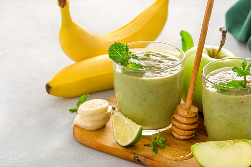 Healthy clean eating concept. Green health smoothie of apple spinach lime and honey on table with copy space