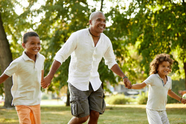 istock Two sons and their father holding hands and running in the park 1396480376