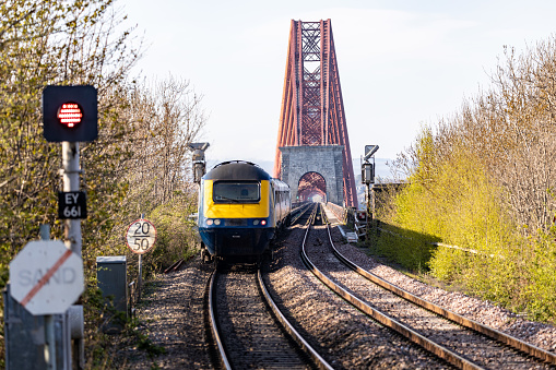 ScotRail Train at Southqueens Ferry Scotland crosses the Forth Rail Bridge. Signal has turned red