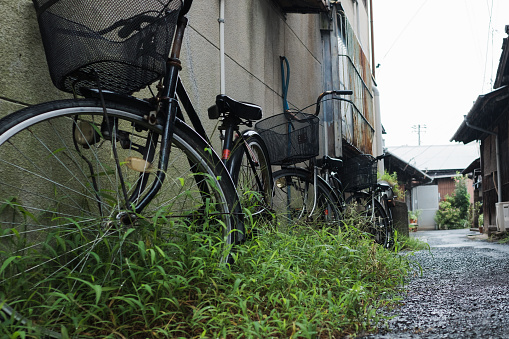 Abandoned bicycle in rainy alley.