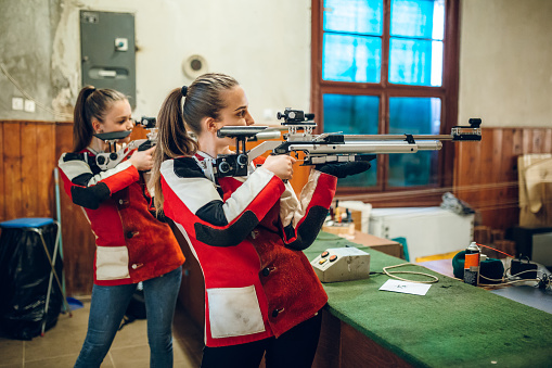 Two young caucasian women having sport shooter training.