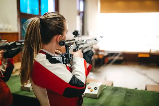Young caucasian woman at sport shooter training.