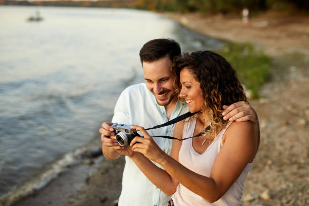Couple in love looking at photos on camera outdoors stock photo