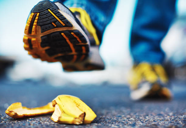 Accident about to happen: foot stepping on a banana skin Danger under foot as shoe is about to slip on a discarded banana peel. slippery unrecognizable person safety outdoors stock pictures, royalty-free photos & images