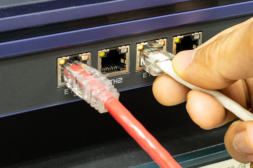 Hand of a man holding The network cables to connect the port of a switch to connect internet network, concept Communication technology